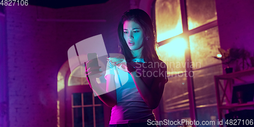 Image of Cinematic portrait of handsome young woman in neon lighted interior