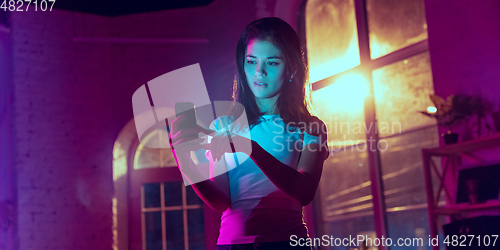 Image of Cinematic portrait of handsome young woman in neon lighted interior