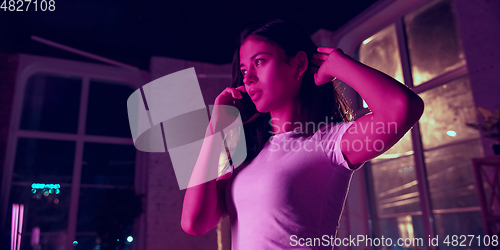 Image of Cinematic portrait of handsome young woman in neon lighted interior