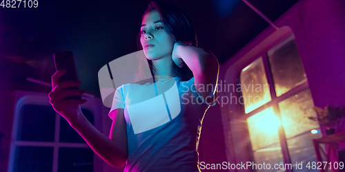 Image of Cinematic portrait of handsome young woman in neon lighted interior