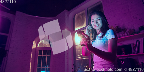 Image of Cinematic portrait of handsome young woman in neon lighted interior