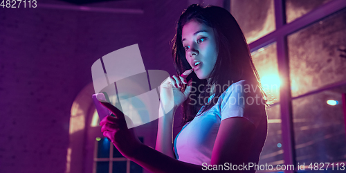 Image of Cinematic portrait of handsome young woman in neon lighted interior