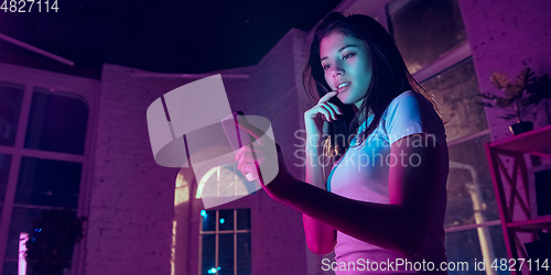 Image of Cinematic portrait of handsome young woman in neon lighted interior