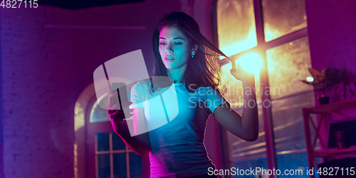 Image of Cinematic portrait of handsome young woman in neon lighted interior