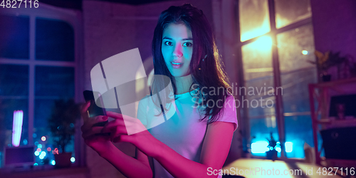 Image of Cinematic portrait of handsome young woman in neon lighted interior