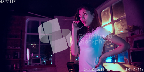 Image of Cinematic portrait of handsome young woman in neon lighted interior