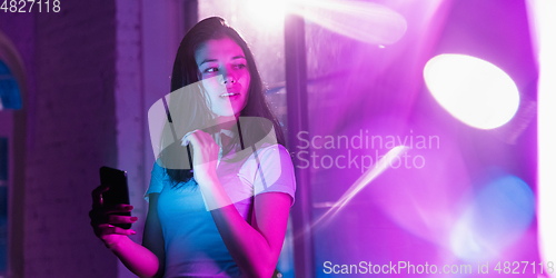 Image of Cinematic portrait of handsome young woman in neon lighted interior