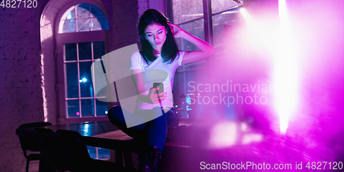 Image of Cinematic portrait of handsome young woman in neon lighted interior