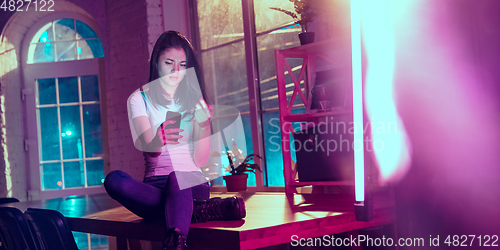 Image of Cinematic portrait of handsome young woman in neon lighted interior