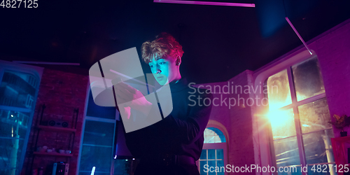 Image of Cinematic portrait of handsome young man in neon lighted interior