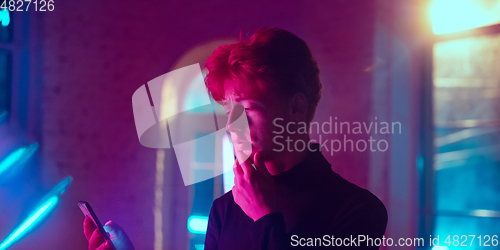 Image of Cinematic portrait of handsome young man in neon lighted interior