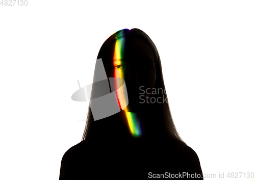 Image of Dramatic portrait of a girl in the dark on white studio background with rainbow colored line