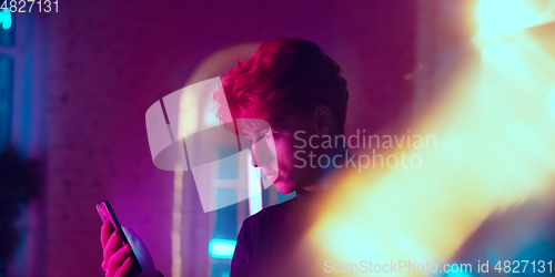 Image of Cinematic portrait of handsome young man in neon lighted interior