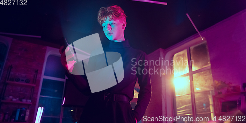 Image of Cinematic portrait of handsome young man in neon lighted interior