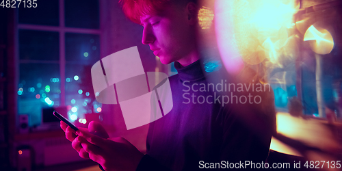 Image of Cinematic portrait of handsome young man in neon lighted interior