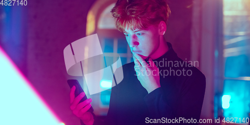 Image of Cinematic portrait of handsome young man in neon lighted interior