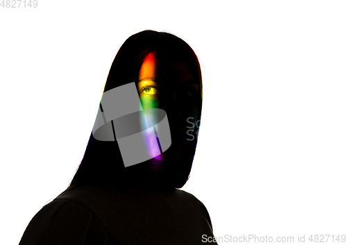 Image of Dramatic portrait of a girl in the dark on white studio background with rainbow colored line