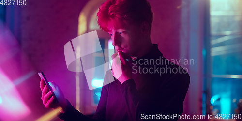 Image of Cinematic portrait of handsome young man in neon lighted interior