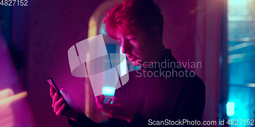 Image of Cinematic portrait of handsome young man in neon lighted interior