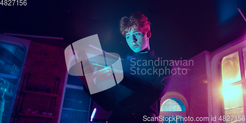 Image of Cinematic portrait of handsome young man in neon lighted interior