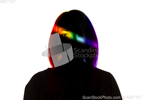 Image of Dramatic portrait of a girl in the dark on white studio background with rainbow colored line