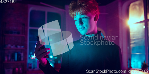 Image of Cinematic portrait of handsome young man in neon lighted interior