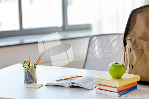 Image of books, apple and school supplies on table at home