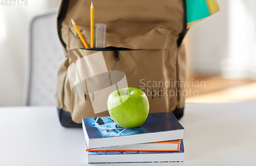 Image of school backpack with books and apple on table