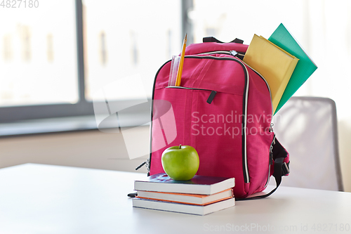 Image of pink backpack, apple and school supplies on table