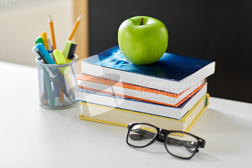 Image of books, apple and school supplies on table at home