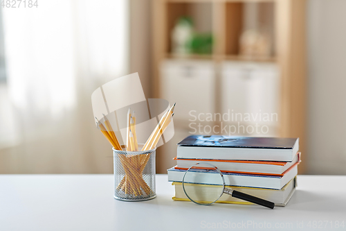 Image of book with magnifier and pencil on table at home