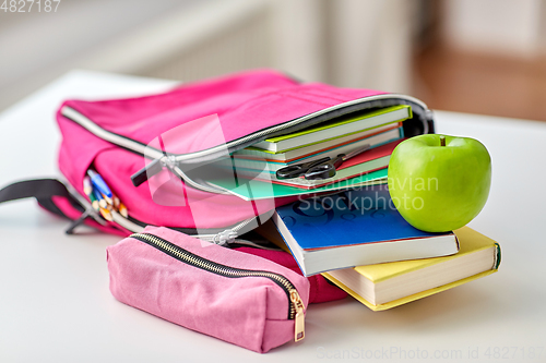 Image of backpack, apple and school supplies on table