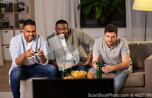 Image of happy friends playing video games at home at night