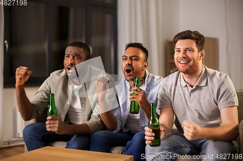 Image of happy male friends or fans drinking beer at home