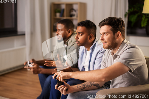 Image of happy friends playing video games at home at night