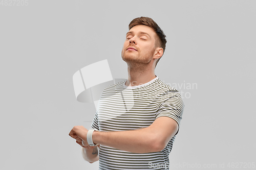 Image of calm young man with smart watch meditating