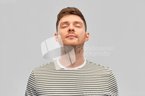 Image of happy young man in striped t-shirt breathing