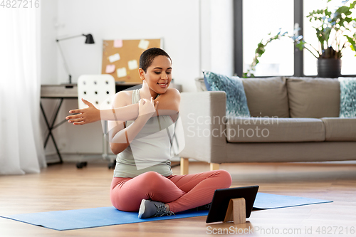 Image of happy woman with tablet pc doing sports at home