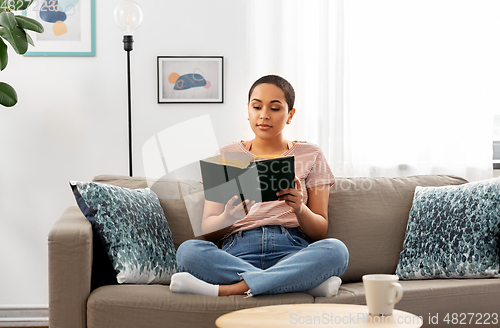 Image of african american woman reading book at home