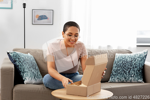 Image of african american woman opening parcel box at home