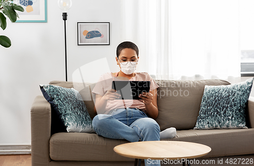 Image of woman in medical mask with tablet pc at home