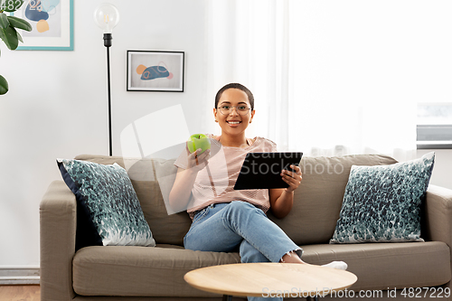 Image of african woman with tablet pc and apple at home