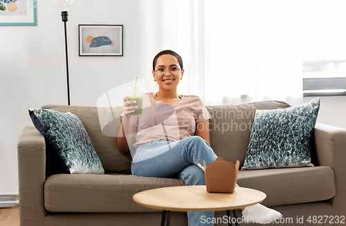 Image of african american woman drinking smoothie at home