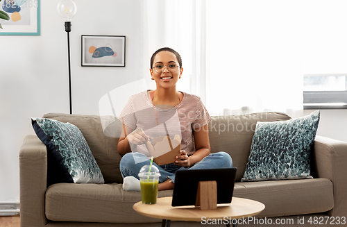 Image of african woman eating food with chopsticks at home