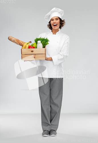 Image of happy smiling female chef with food in wooden box