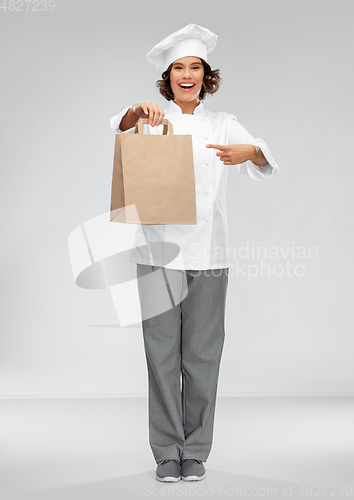 Image of happy female chef with takeaway food in paper bag