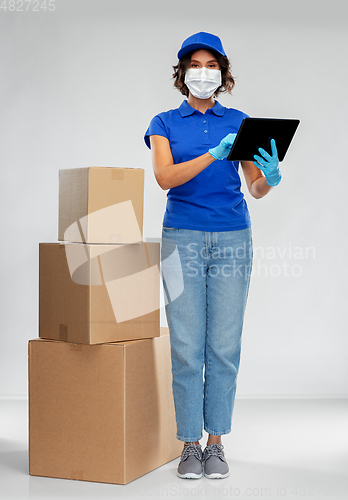 Image of delivery woman in mask with boxes and tablet pc