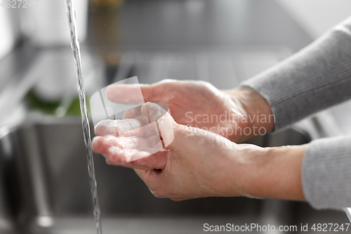 Image of woman washing hands with soap in kitchen