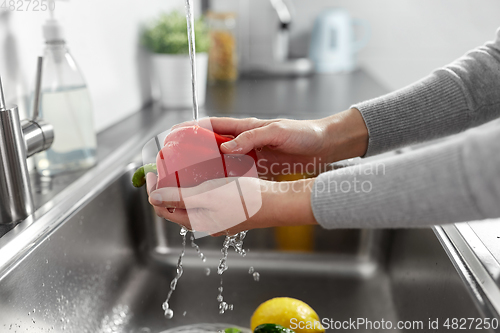 Image of woman washing fruits and vegetables in kitchen