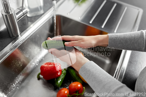 Image of close up of woman washing vegetables in kitchen